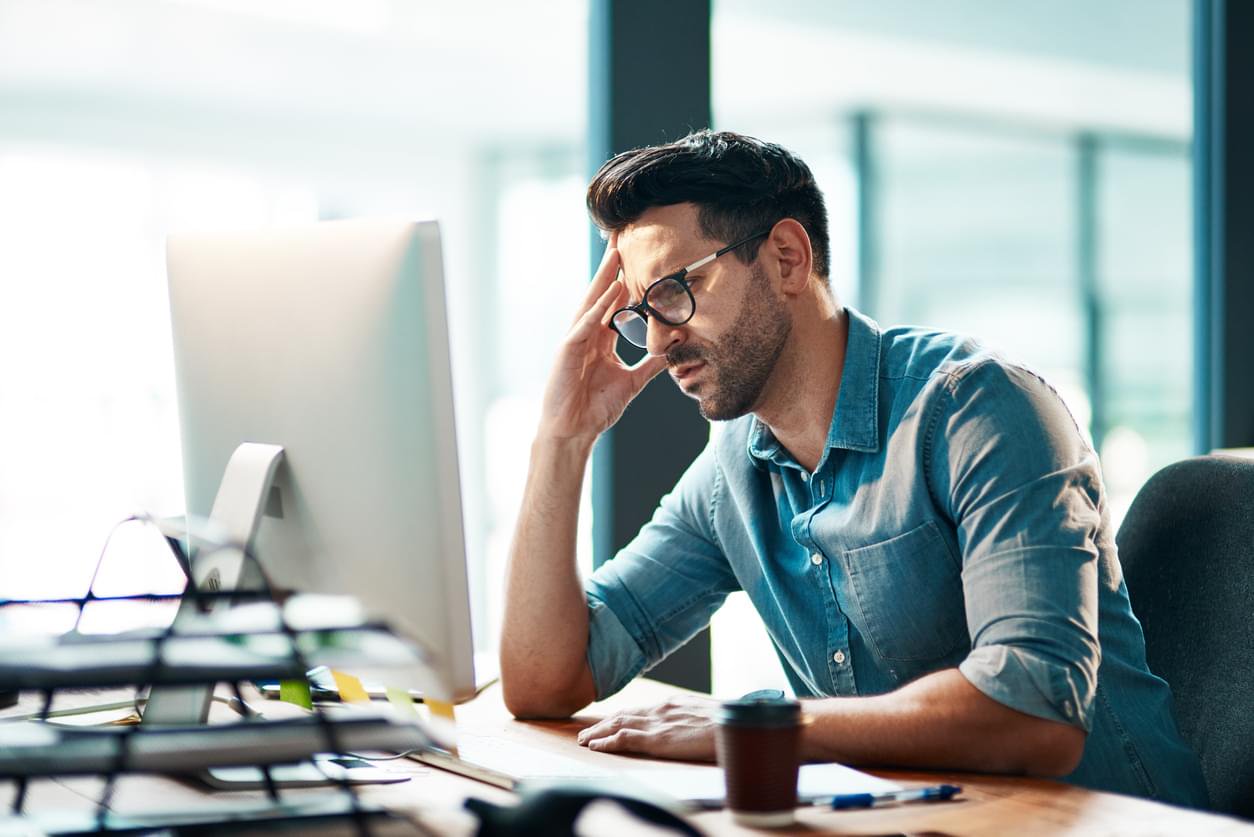 A man in glasses experiencing stress or a headache while working