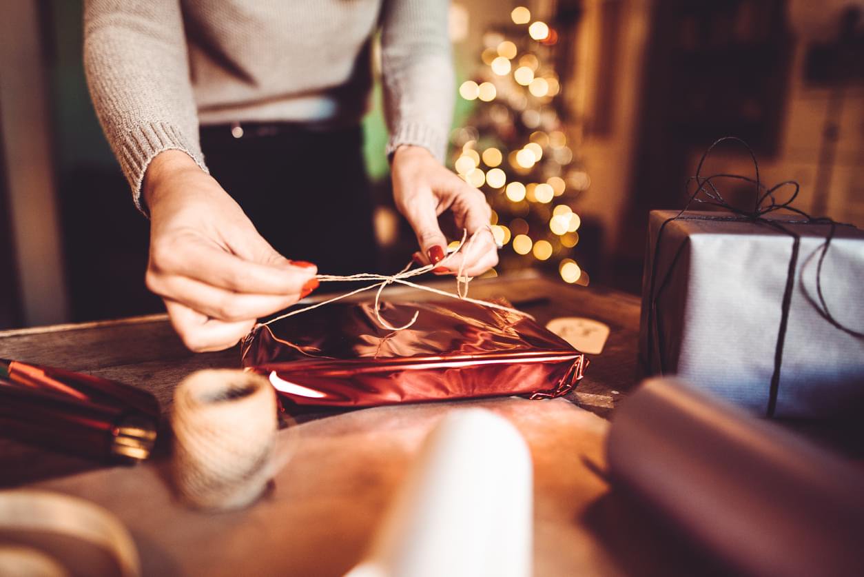 Hands skillfully wrap a gift, symbolizing self-care during the holidays