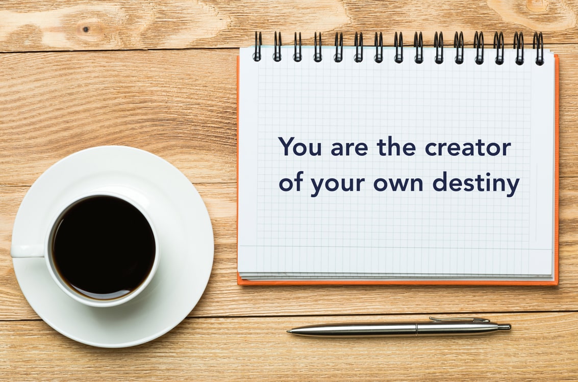 Motivational quote 'You are the creator of your own destiny' on a notepad
