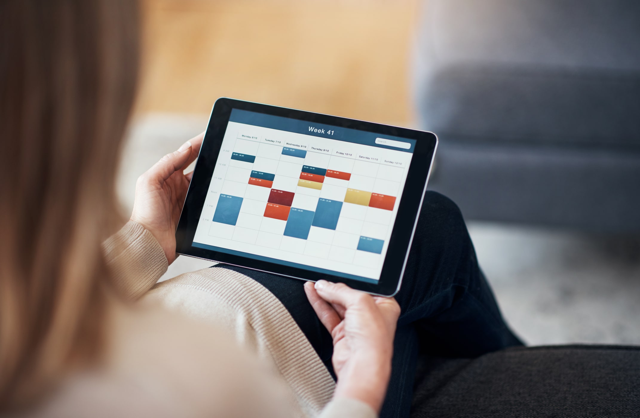 Person organizing schedule on a tablet, emphasizing time management
