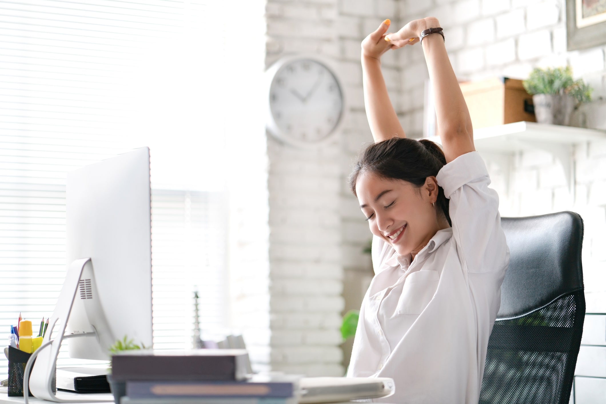 Joyful employee stretching at her desk, practicing workplace gratitude